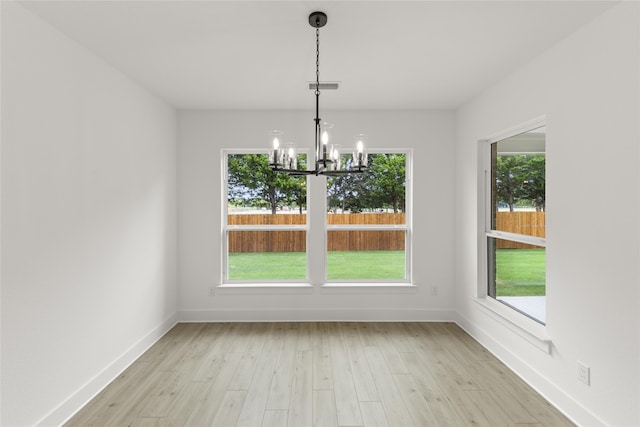 unfurnished dining area featuring a wealth of natural light, a notable chandelier, and light hardwood / wood-style flooring