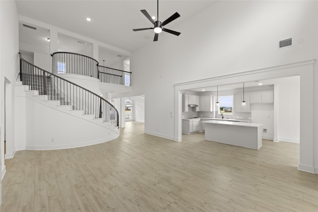 unfurnished living room featuring ceiling fan, sink, high vaulted ceiling, and light hardwood / wood-style floors