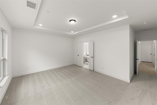 carpeted spare room featuring a raised ceiling