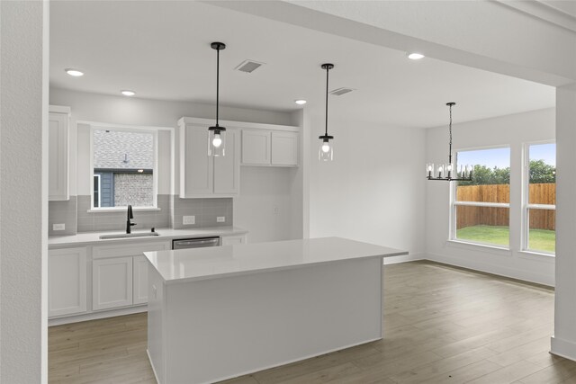 kitchen featuring light hardwood / wood-style flooring, a kitchen island, white cabinets, and hanging light fixtures