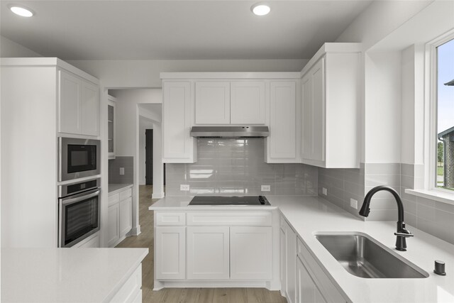 kitchen featuring sink, appliances with stainless steel finishes, white cabinetry, and light hardwood / wood-style floors