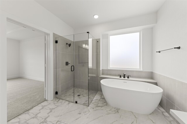 bathroom featuring tile walls and shower with separate bathtub