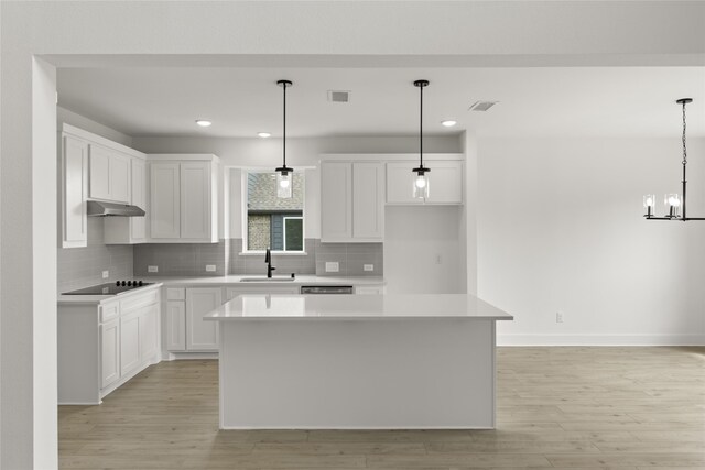 kitchen with a center island, light hardwood / wood-style flooring, white cabinetry, sink, and pendant lighting