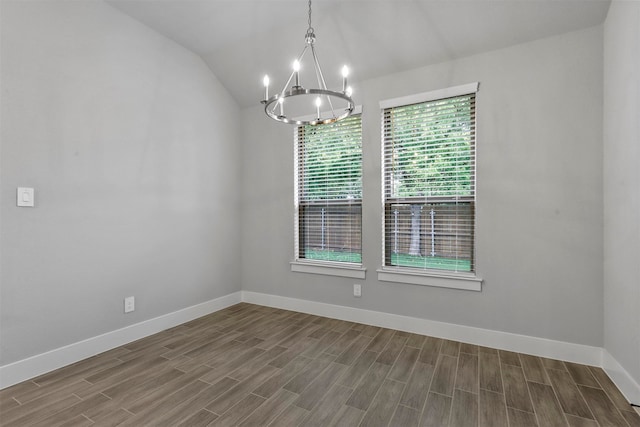 empty room with wood-type flooring, vaulted ceiling, and a notable chandelier