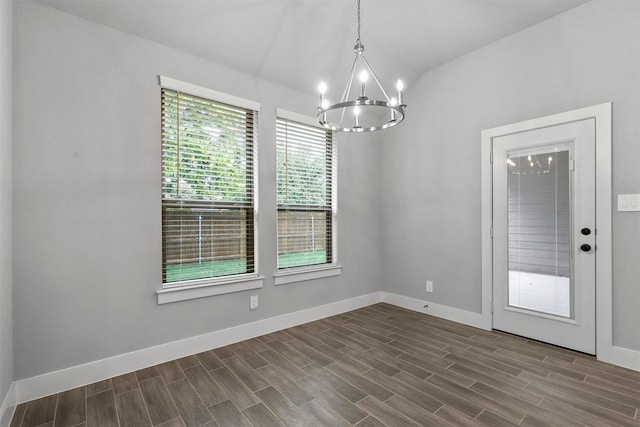 unfurnished dining area with wood-type flooring, a chandelier, and lofted ceiling