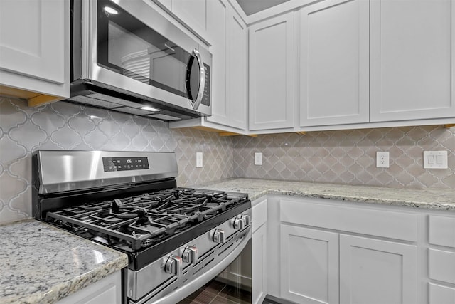 kitchen with stainless steel appliances, white cabinets, and decorative backsplash