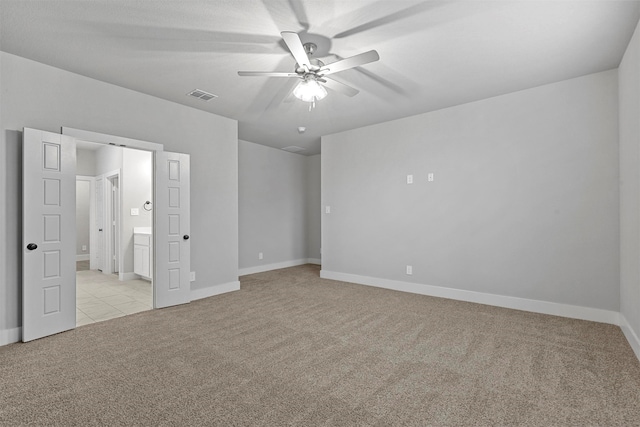 unfurnished bedroom featuring ceiling fan, ensuite bath, and light colored carpet