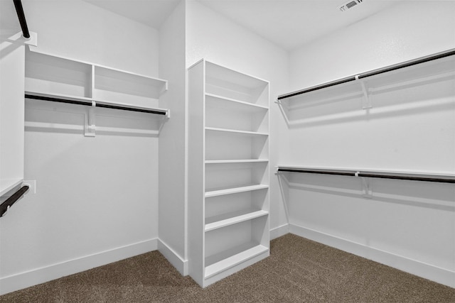 walk in closet with dark carpet