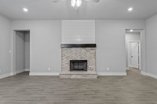 unfurnished living room featuring a brick fireplace, ceiling fan, and light hardwood / wood-style flooring