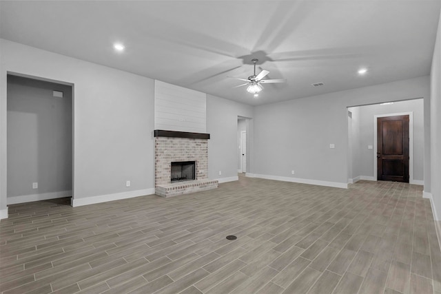 unfurnished living room with a brick fireplace, ceiling fan, and light hardwood / wood-style flooring