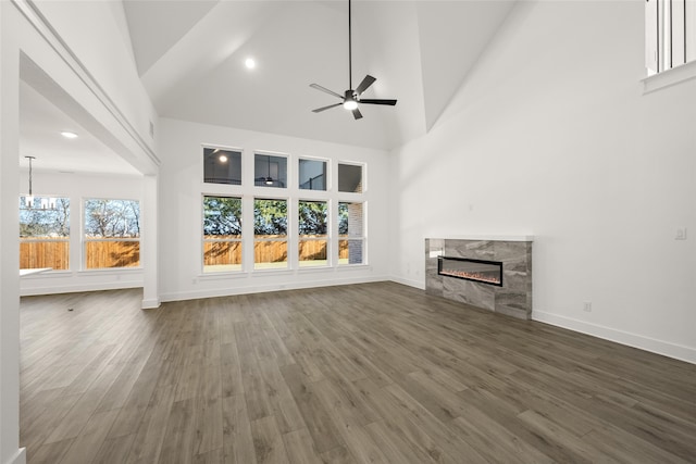 unfurnished living room featuring ceiling fan with notable chandelier, dark hardwood / wood-style floors, a premium fireplace, and high vaulted ceiling