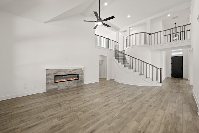 unfurnished living room featuring a fireplace, high vaulted ceiling, light hardwood / wood-style floors, and ceiling fan