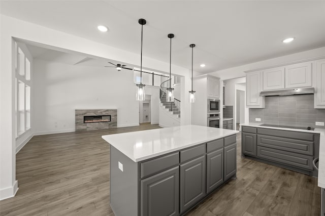 kitchen featuring gray cabinetry, a fireplace, white cabinets, a kitchen island, and decorative backsplash