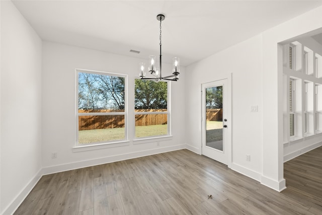 unfurnished dining area featuring wood-type flooring and a notable chandelier