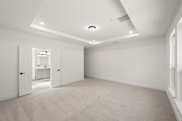 unfurnished room featuring crown molding, light colored carpet, and a tray ceiling