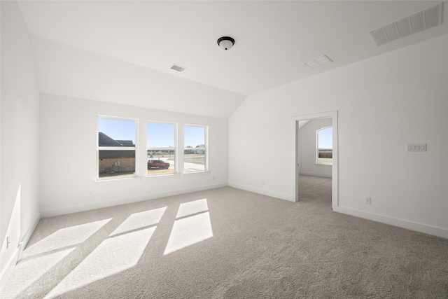 carpeted spare room featuring a healthy amount of sunlight and vaulted ceiling