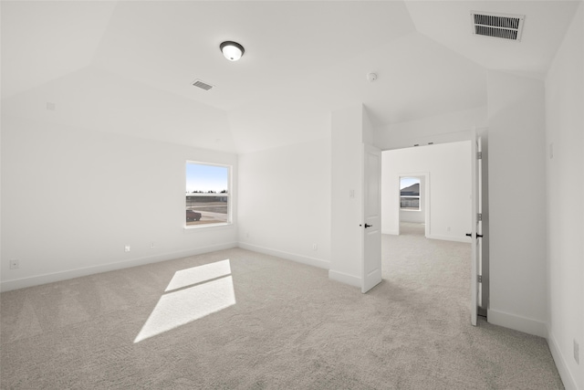 spare room featuring vaulted ceiling and light colored carpet