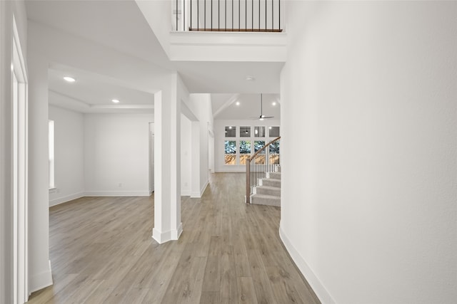 hallway with a towering ceiling and light wood-type flooring