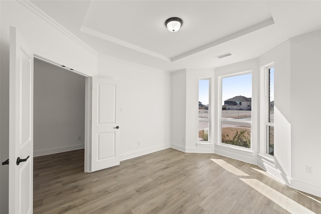 spare room featuring crown molding, a tray ceiling, and light hardwood / wood-style flooring