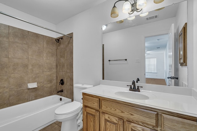 full bathroom with tile flooring, tiled shower / bath, vanity, and toilet