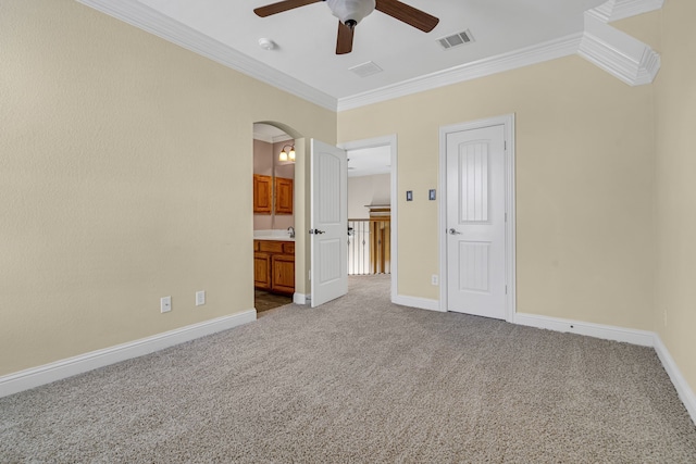 unfurnished bedroom with ornamental molding, carpet flooring, ensuite bathroom, and ceiling fan