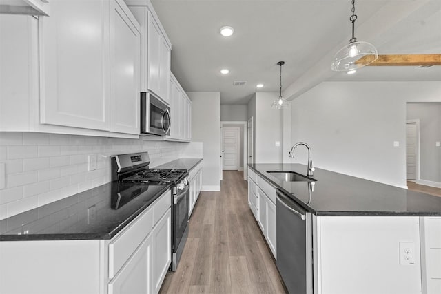 kitchen with light wood finished floors, visible vents, an island with sink, stainless steel appliances, and a sink