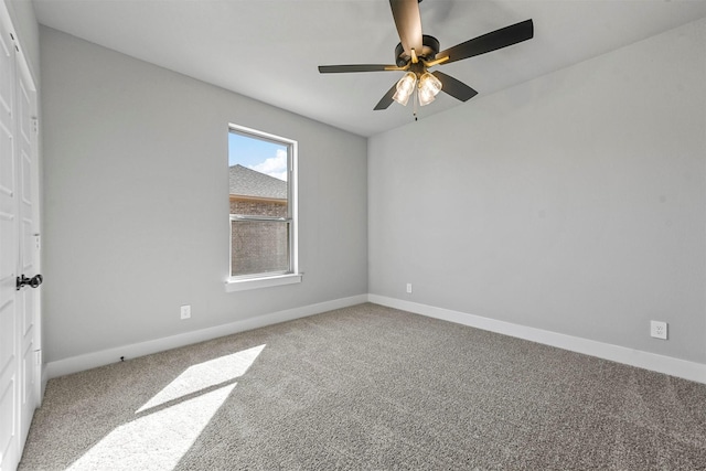 carpeted spare room featuring a ceiling fan and baseboards