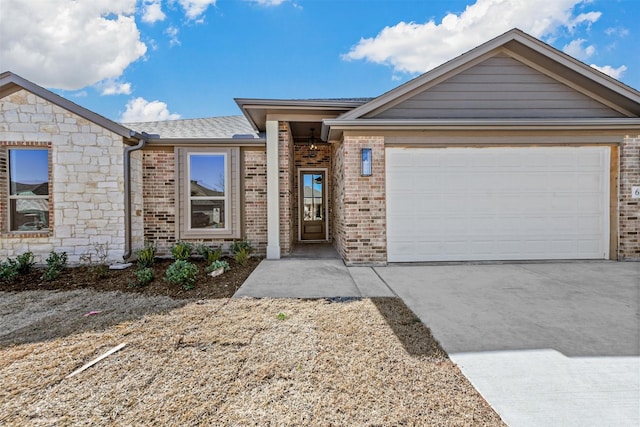 view of front of house featuring a garage, brick siding, a shingled roof, concrete driveway, and stone siding