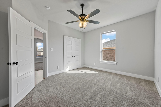 unfurnished bedroom with a closet, carpet flooring, a ceiling fan, and baseboards