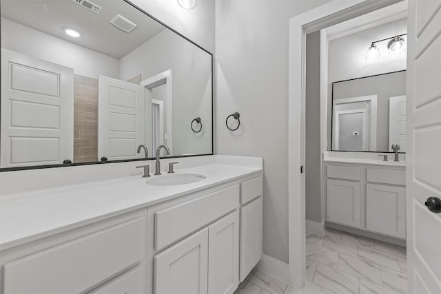 full bathroom featuring marble finish floor, two vanities, a sink, and visible vents