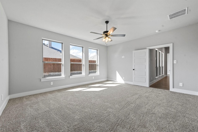 carpeted spare room featuring a ceiling fan, visible vents, and baseboards