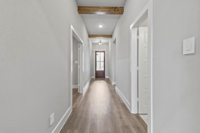 doorway to outside with beamed ceiling, baseboards, and wood finished floors