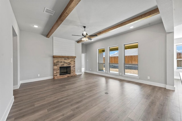 unfurnished living room featuring visible vents, baseboards, a brick fireplace, beam ceiling, and dark wood-style floors