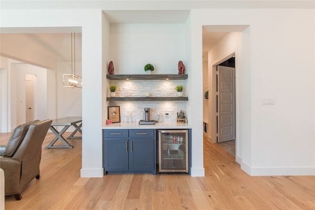 bar featuring beverage cooler, backsplash, light wood-type flooring, and blue cabinets