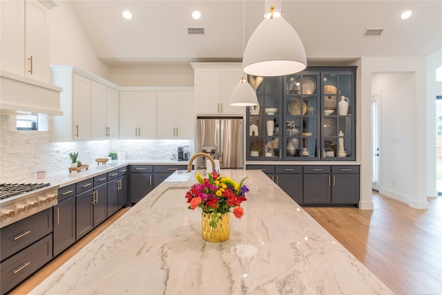 kitchen with hanging light fixtures, white cabinets, and appliances with stainless steel finishes