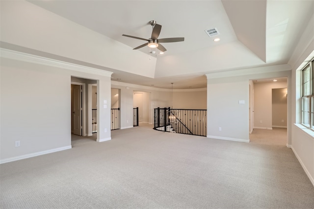 unfurnished room with ceiling fan, light colored carpet, a tray ceiling, and ornamental molding