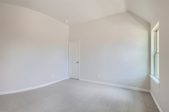 carpeted spare room featuring lofted ceiling