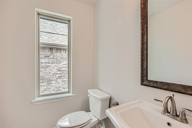 bathroom featuring toilet, a healthy amount of sunlight, and sink