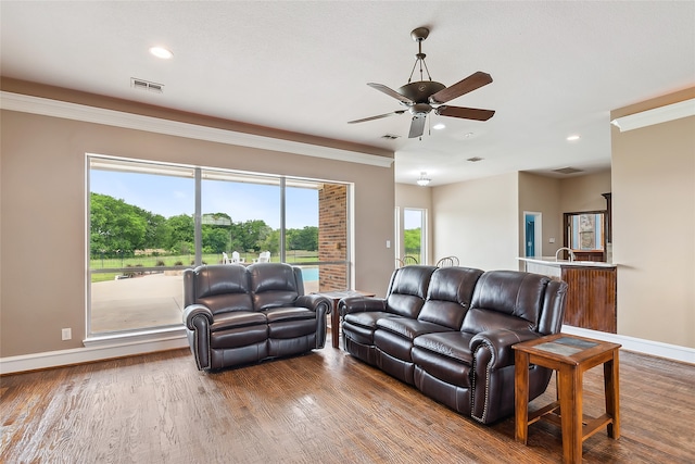 living room featuring hardwood / wood-style flooring, ornamental molding, and ceiling fan