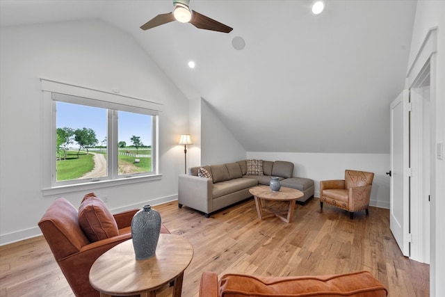 living room with ceiling fan, light hardwood / wood-style floors, and vaulted ceiling