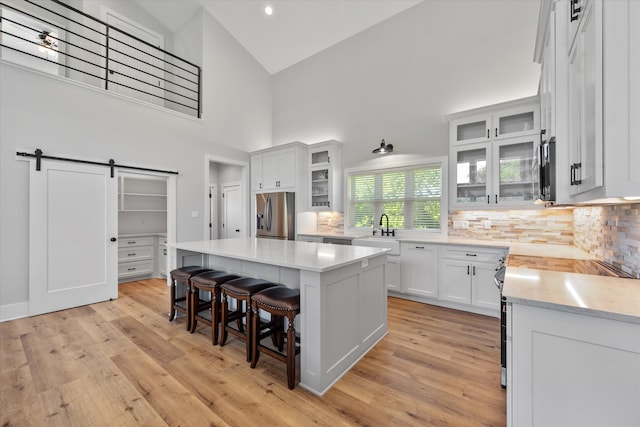 kitchen with stainless steel appliances, white cabinetry, a center island, and backsplash