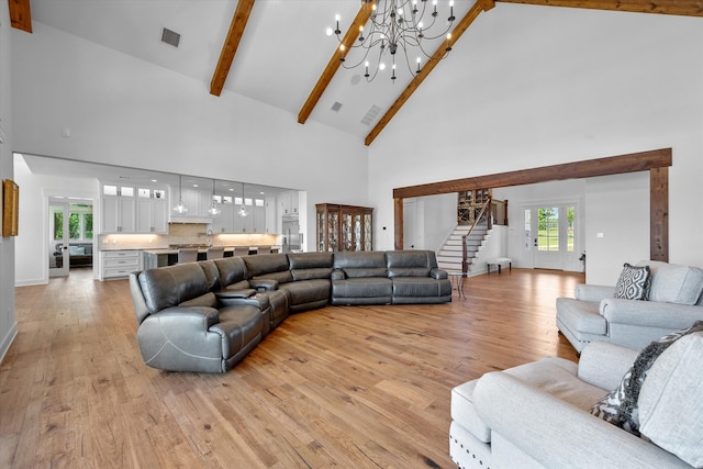 living room with high vaulted ceiling, a chandelier, beam ceiling, and light wood-type flooring