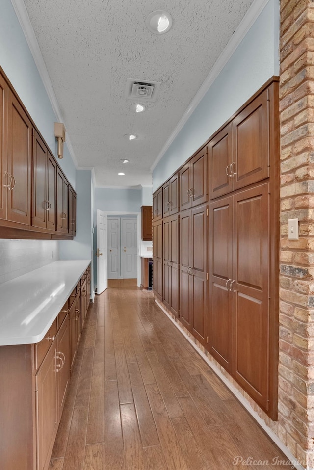 kitchen with a textured ceiling, light hardwood / wood-style floors, and crown molding