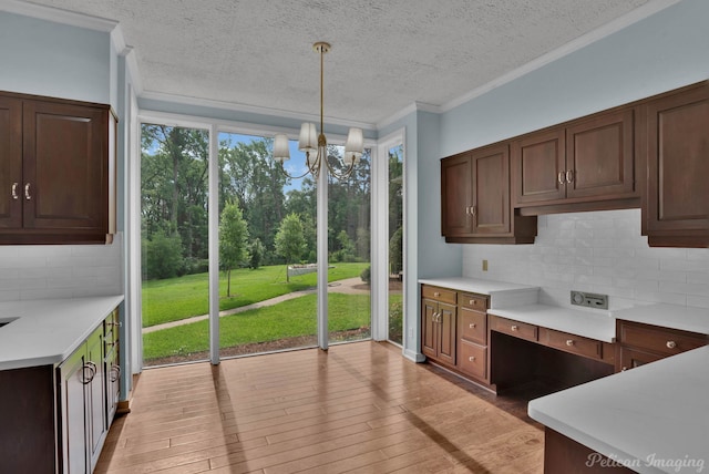 kitchen with pendant lighting, tasteful backsplash, light wood-type flooring, and a chandelier