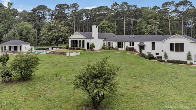 back of house with a lawn and an outdoor structure