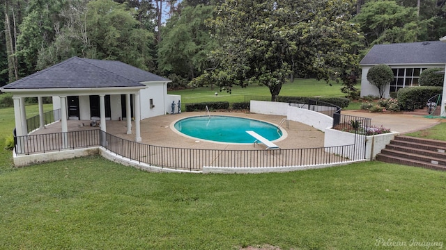 view of pool featuring a lawn, a diving board, and a patio