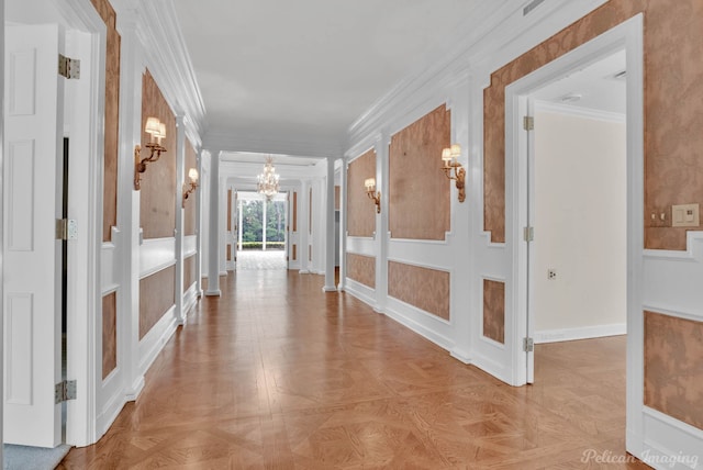 hallway with decorative columns, light parquet flooring, a notable chandelier, and ornamental molding