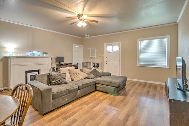 living room with a brick fireplace, ceiling fan, light hardwood / wood-style flooring, and crown molding