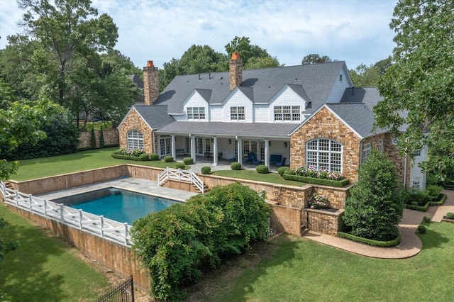 back of property with a patio, a fenced in pool, and a lawn