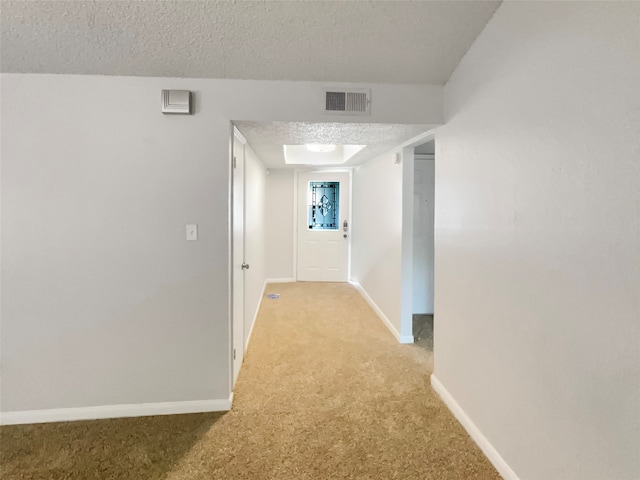 hall featuring light carpet and a textured ceiling